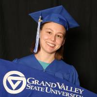 person in cap and gown holding gvsu flag